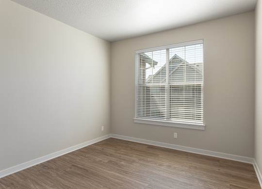 A room with a window and wooden flooring.