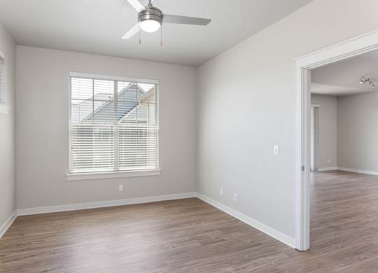 A room with a ceiling fan and a window with blinds.