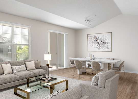A modern living room with a grey sofa, a glass coffee table, and a dining table set up.