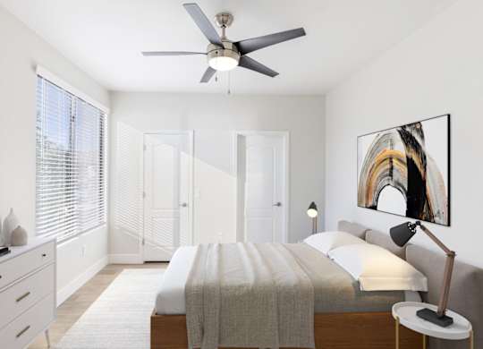 A bedroom with a bed, a ceiling fan, and a painting on the wall.