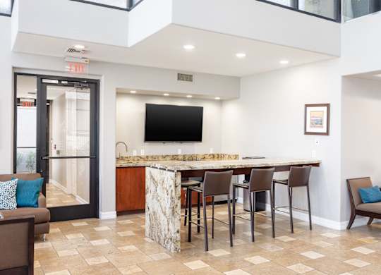A kitchen area with a bar and chairs.