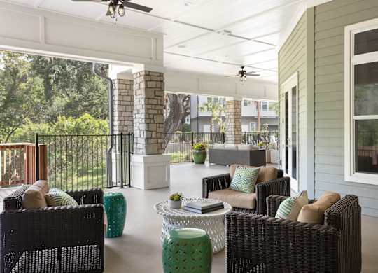 A patio with a black wicker sofa and a white table.