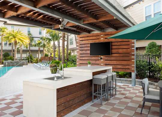 A patio with a bar and chairs under a roof.