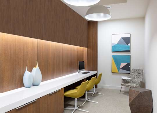 A room with a white desk, yellow chairs, and a brown wall.