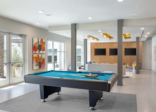 A pool table in a room with a wooden cabinet and a painting on the wall.