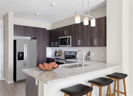 A kitchen with a granite countertop and stools.