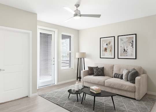 A living room with a couch, a table, and a ceiling fan.