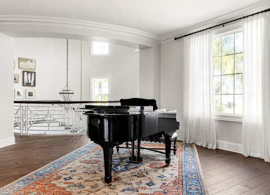 A black grand piano sits in a room with a white piano bench.