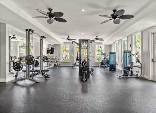 A spacious gym with a variety of equipment and a ceiling fan.