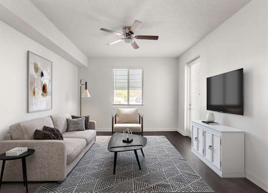 A living room with a beige couch, a black coffee table, and a flat screen TV mounted on the wall.