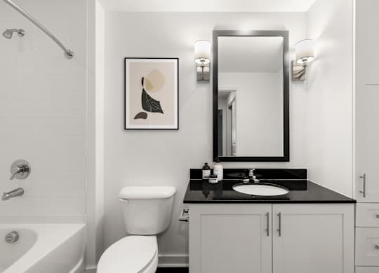 A bathroom with a white toilet, sink, and a framed picture on the wall.