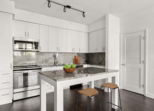 A kitchen with a marble countertop and white cabinets.