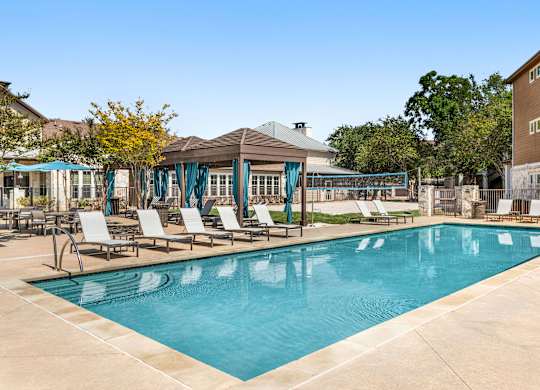 A large swimming pool with lounge chairs and a gazebo.