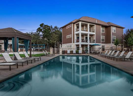 A large swimming pool in front of a multi-story apartment building.