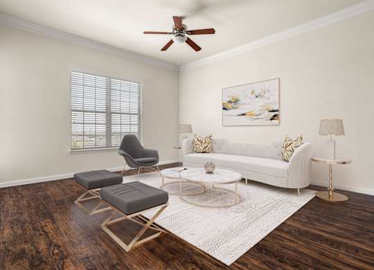 A living room with a white couch, a chair, a coffee table, and a painting on the wall.