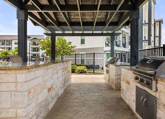 A patio with a grill and a stone wall.