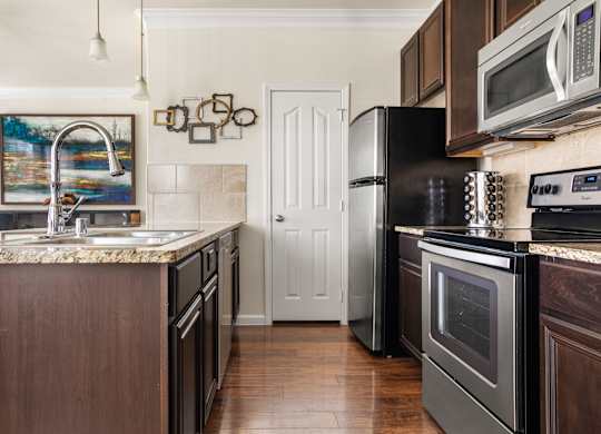 A kitchen with dark wood cabinets and black appliances.