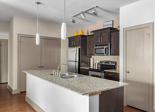 A kitchen with a granite countertop and stainless steel appliances.