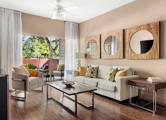 A living room with a white couch and a glass coffee table.
