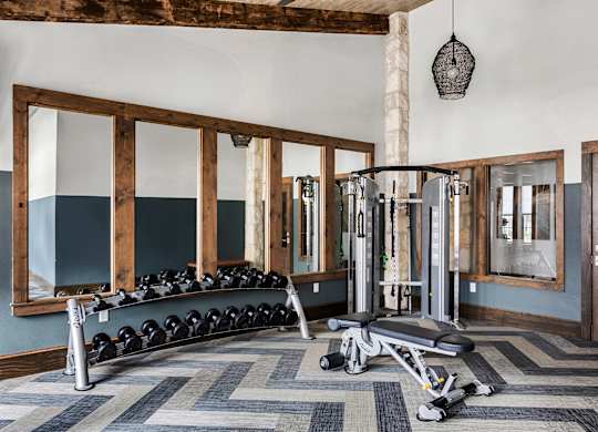 A gym with a bench, weights, and mirrors.