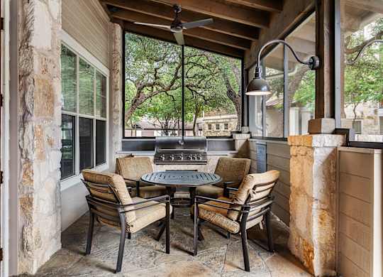 A patio with a table and chairs and a ceiling fan.