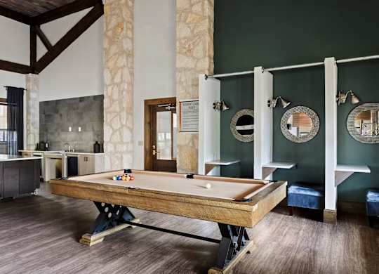 A pool table is in the middle of a room with a green wall.