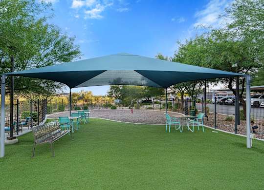 A green park area with a canopy and chairs.