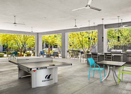 A ping pong table is in the middle of a room with a table and chairs.