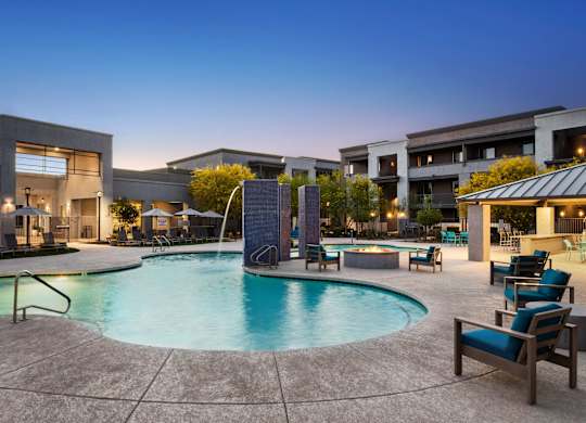 A swimming pool surrounded by lounge chairs and a building in the background.