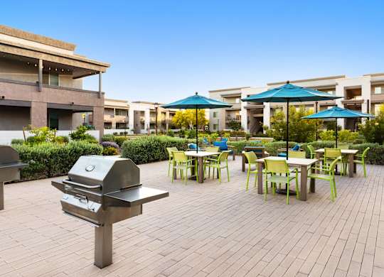 A patio with tables and chairs and umbrellas.