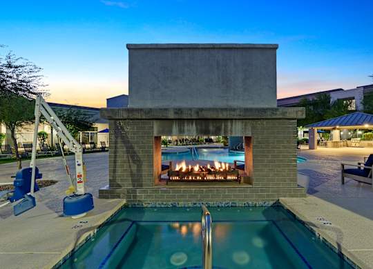 A modern outdoor pool area with a fireplace and lounge chairs.