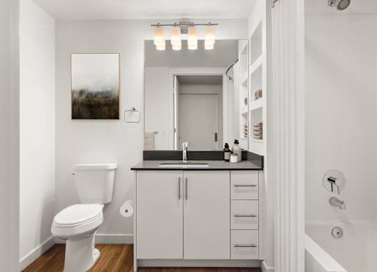 A white bathroom with a toilet, sink, and cabinet.