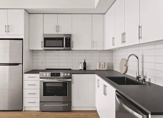 A modern kitchen with a stainless steel refrigerator, oven, and microwave.