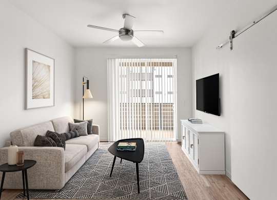 A living room with a couch, a table, a television, and a window with blinds.