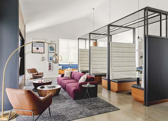 A living room with a purple couch and a black and white striped wall.