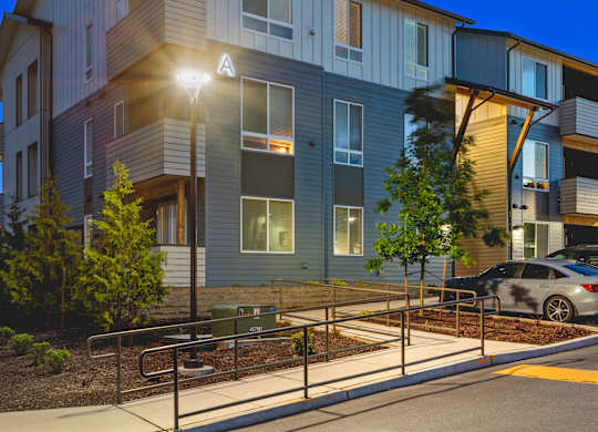 A modern apartment building with a car parked in front.