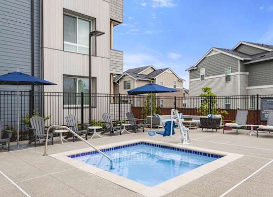 A small pool in a backyard surrounded by chairs and umbrellas.