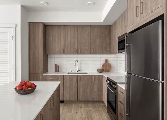A modern kitchen with a bowl of apples on the counter.