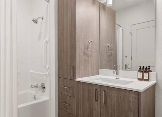 A bathroom with a sink, a shower, and cabinets.