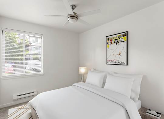 A bedroom with a bed, a ceiling fan, and a picture on the wall.