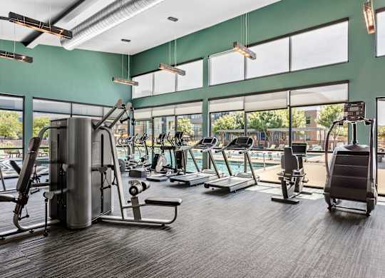 A gym with a variety of equipment including treadmills, weights, and a rowing machine.