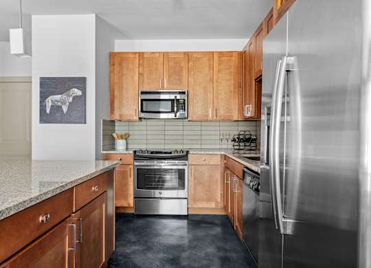 A kitchen with wooden cabinets and a stainless steel refrigerator.