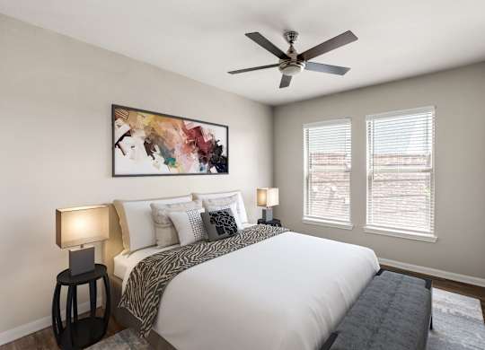 A bedroom with a large bed, two lamps, and a painting on the wall.