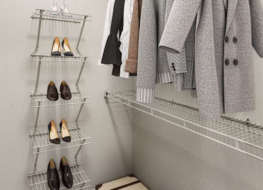 A closet with a coat hanging on a rod and a shelf with shoes.