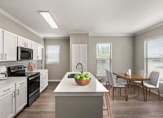 A kitchen with a white countertop and a bowl of green apples on it.