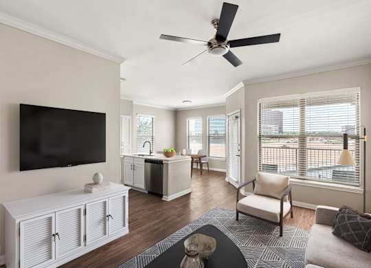 A living room with a television, a couch, and a ceiling fan.