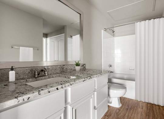 A modern bathroom with a marble countertop and white fixtures.