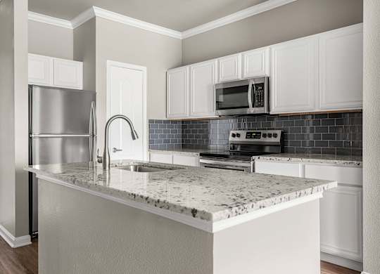 A kitchen with a marble countertop and stainless steel appliances.