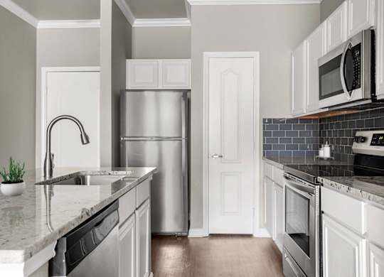 A kitchen with a refrigerator, sink, and oven.