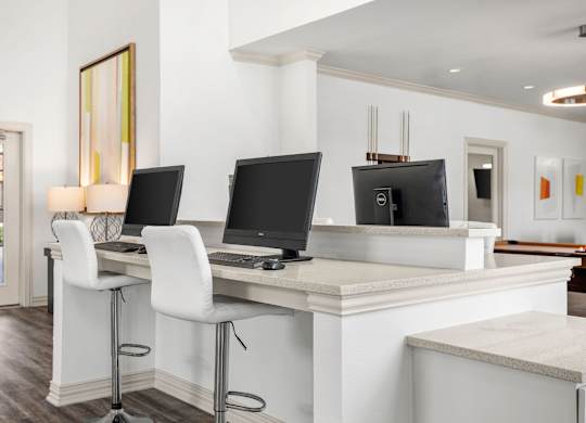 A white desk with two monitors and a laptop.